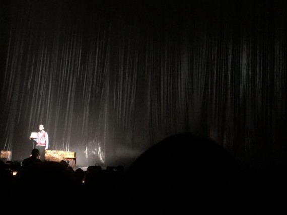 One man on giant dark stage, with spotlight
