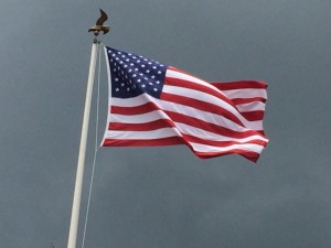 American Flag blowing in the wind with dark skies behind it
