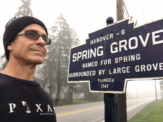 Man standing next to a sign for the small town Spring Grove, Pennsylvania