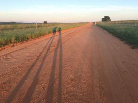 Too long shadows of humans on a dirt road