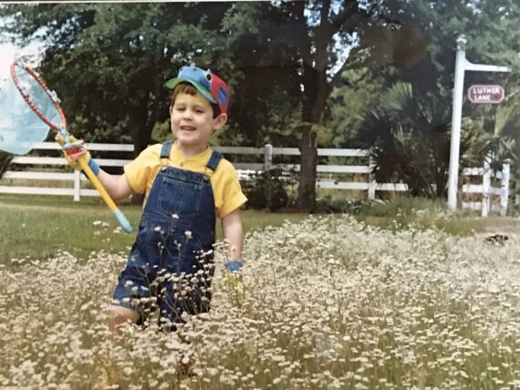 child with butterfly net in flower meadow
