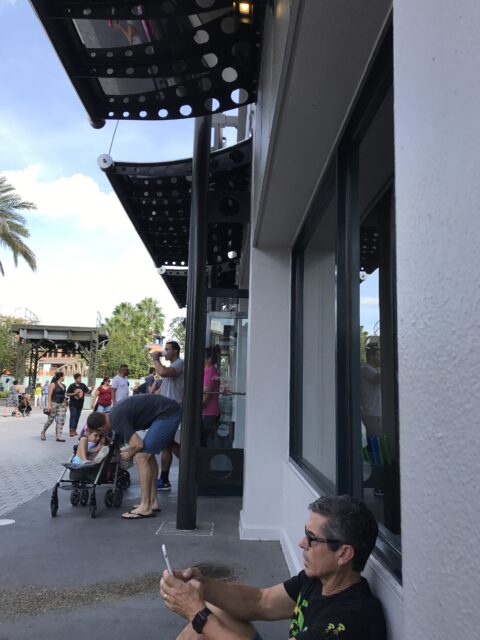 man looking at phone sitting on ground at Disney
