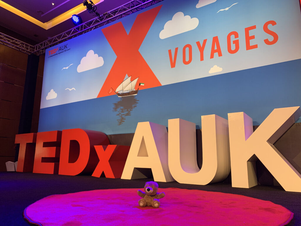 TEDx Talk stage with teddy bear in red dot