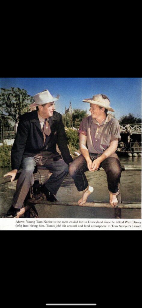 Walt Disney and Tom Nabbe sitting on Disneyland fence