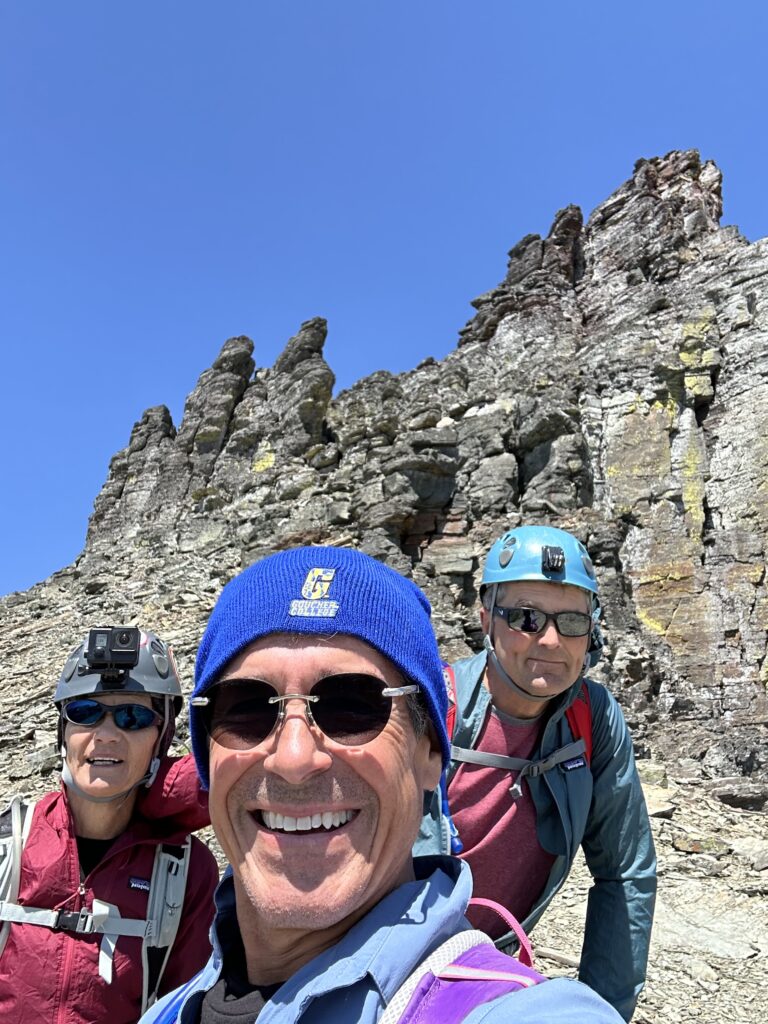 Three adults on a mountain peak
