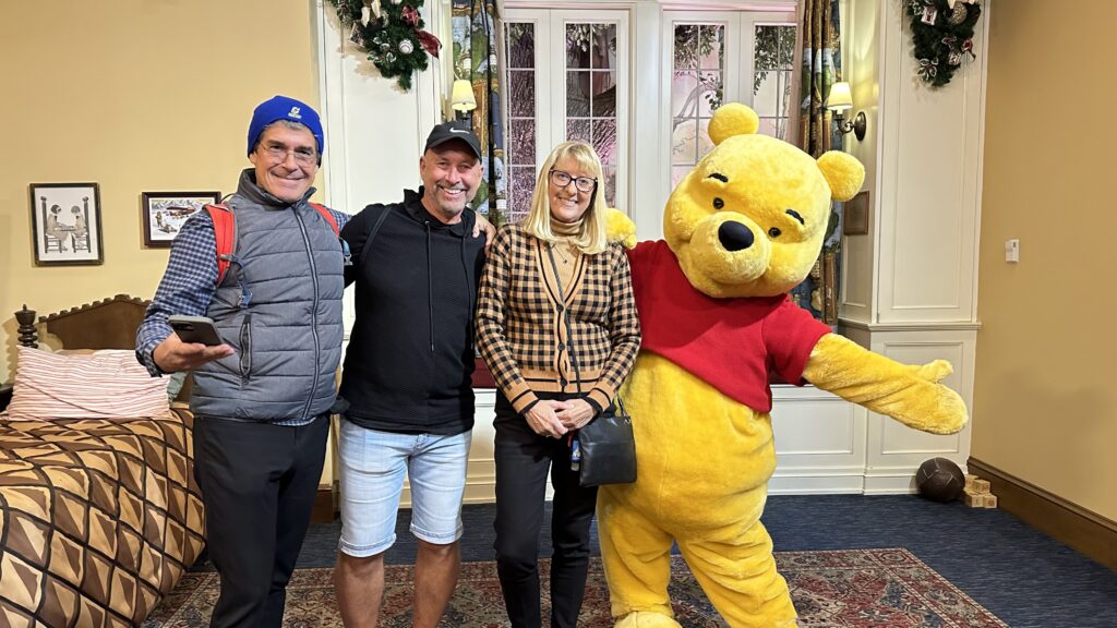 Three adults posing with Winnie the Pooh