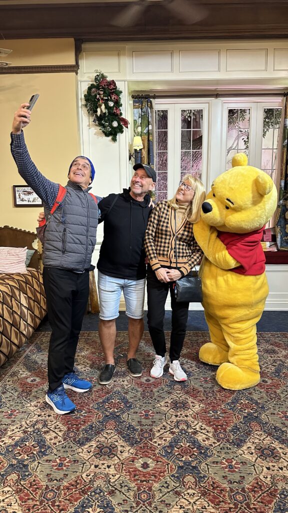 Three adults posing with Winnie the Pooh