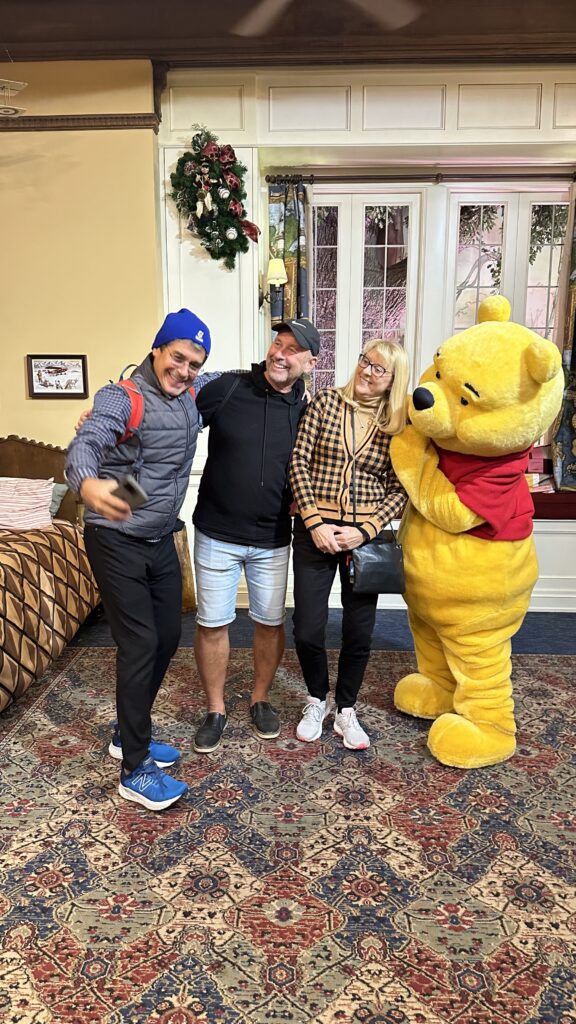 Three adults posing with Winnie the Pooh