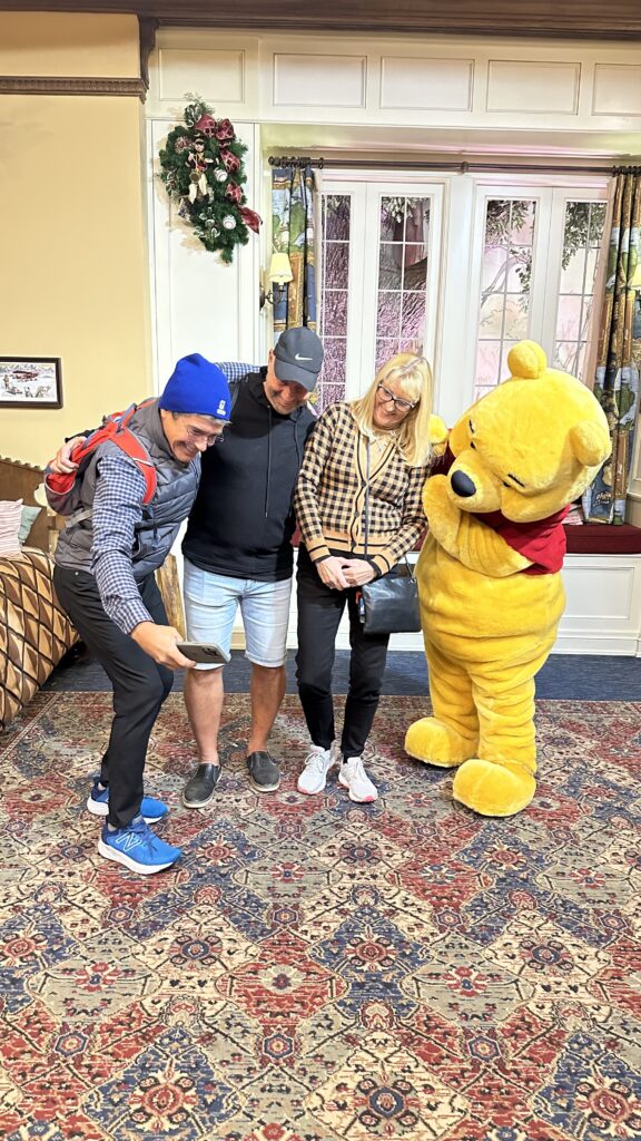 Three adults posing with Winnie the Pooh