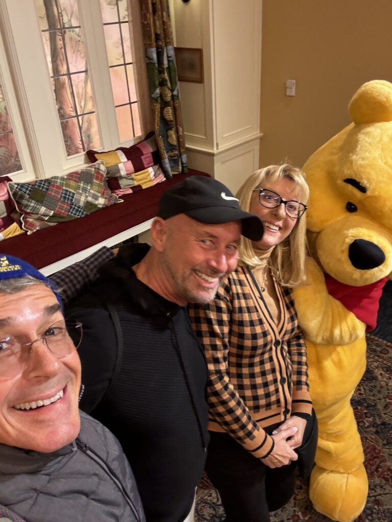 Three adults posing with Winnie the Pooh