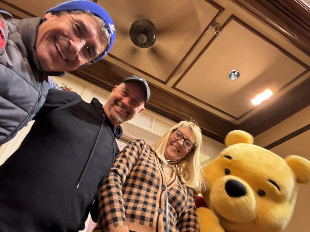 Three adults posing with Winnie the Pooh