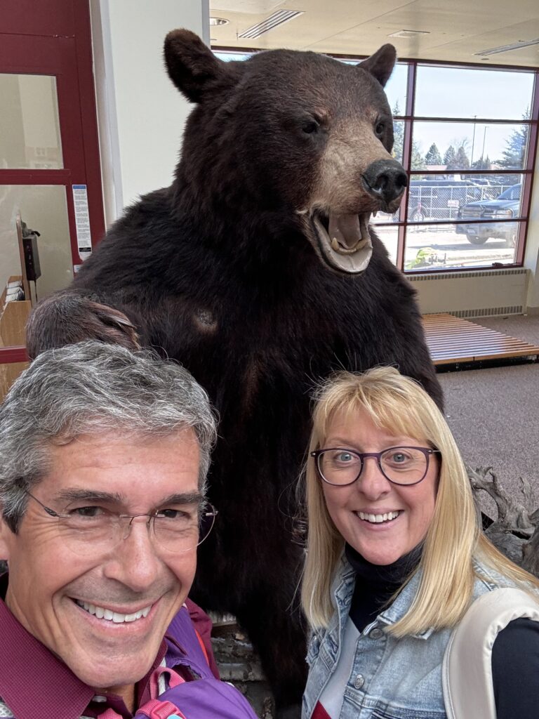 couple posing next to bear statue