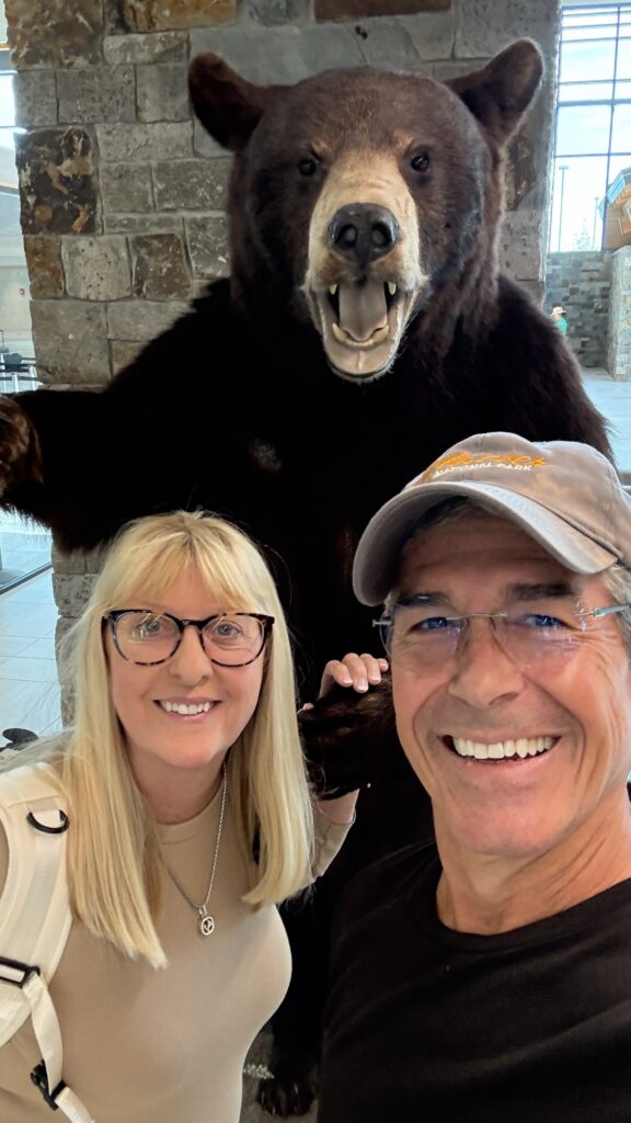 two seniors posing next to stuffed grizzly bear at Glacier airport
